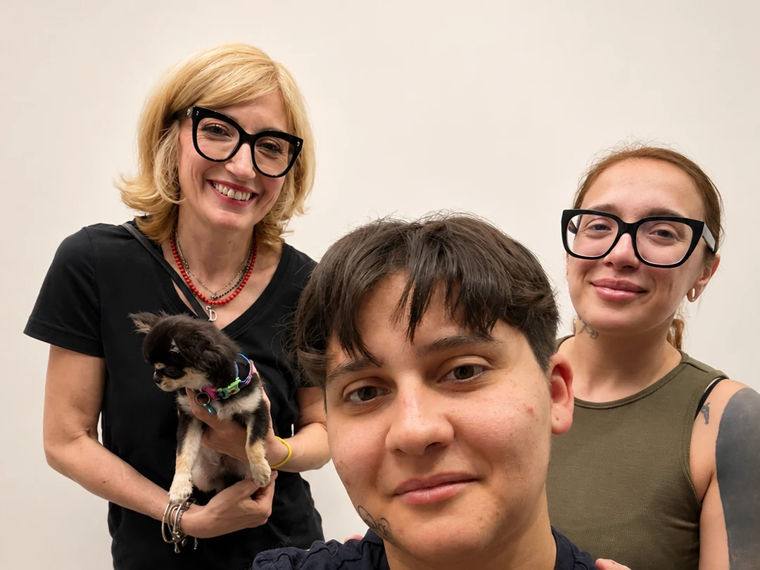 Tre persone sorridono insieme tenendo in braccio un Chihuahua